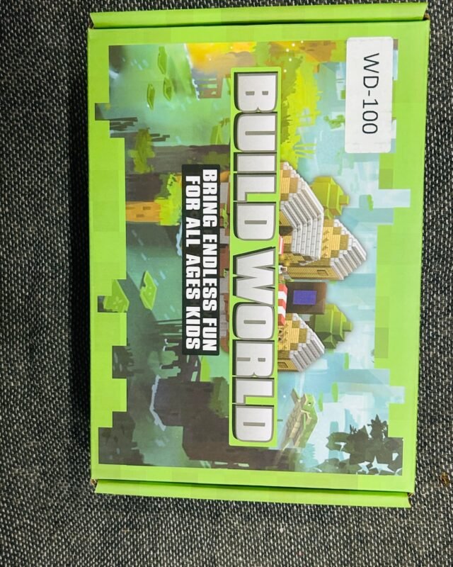 The green box on grey fabric, tilted, its cover a pixel landscape of blocky houses and trees, with a white WD-100 label stuck to one corner.