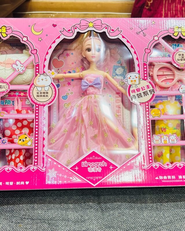 The same box stood upright and photographed from slightly above, the doll and the accessory trays seen at an angle.