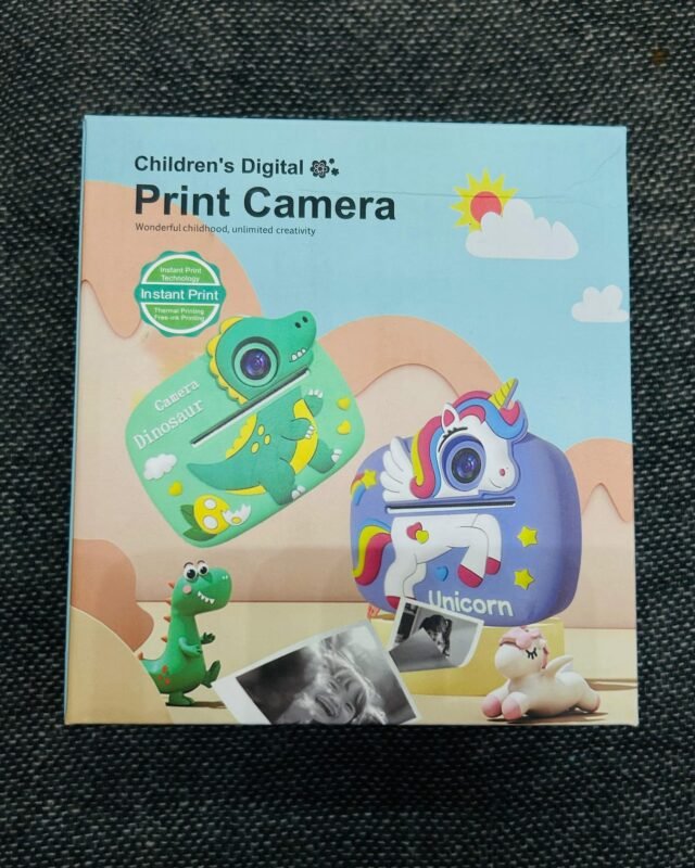 The sealed box upright on dark fabric, its cover printed with the green dinosaur camera and the purple unicorn one against a pale landscape.